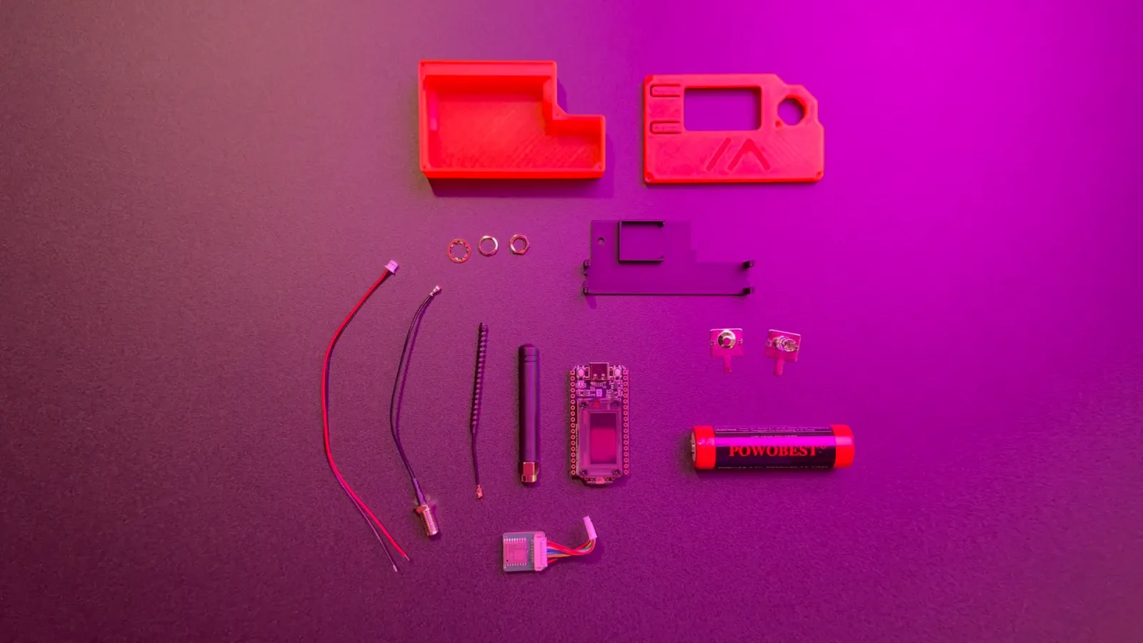 Alle Einzelteile eines Clients ausgelegt — Gehäusehälften, Board, Akku, Antenne, Kabel und Schrauben